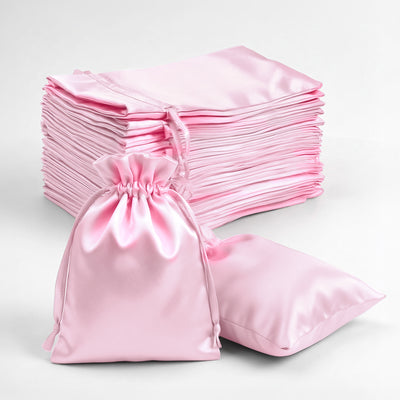 Stack of pink satin bags and one pouch on a plain background