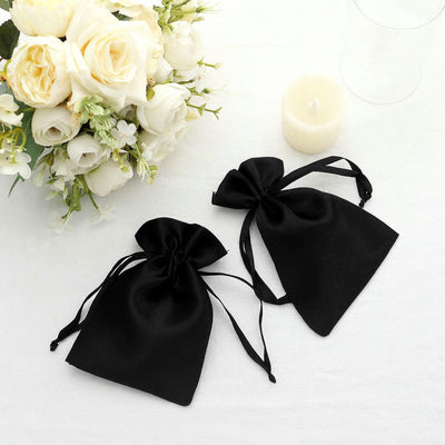 Two elegant black satin drawstring bags on a soft white background.