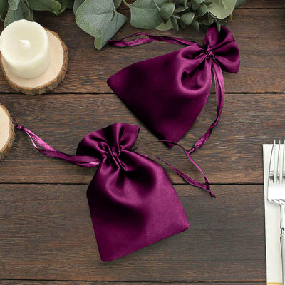 Purple satin drawstring bags on a wooden table.