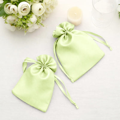 Green satin drawstring bags on a white table with floral decor.