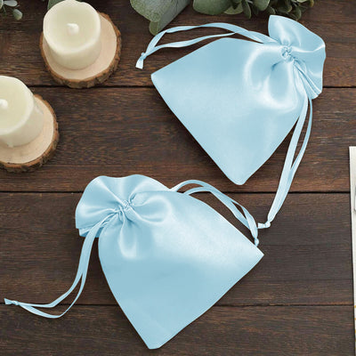 Light blue satin drawstring bags on a wooden surface.