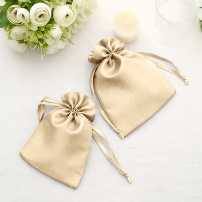 Gold satin drawstring bags on a soft surface with floral accents.