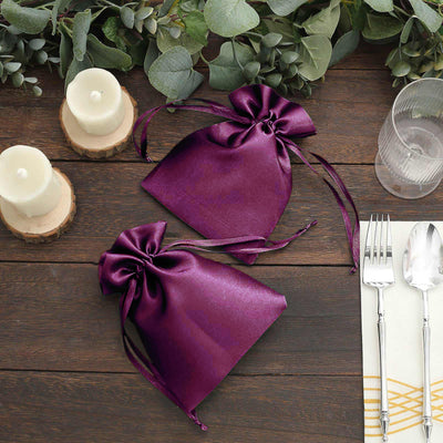 Purple satin gift bags on a rustic table with candles and cutlery.