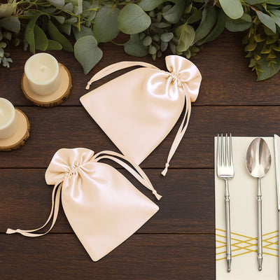 Elegant satin favor bags in blush pink with ribbon ties, perfect for events.