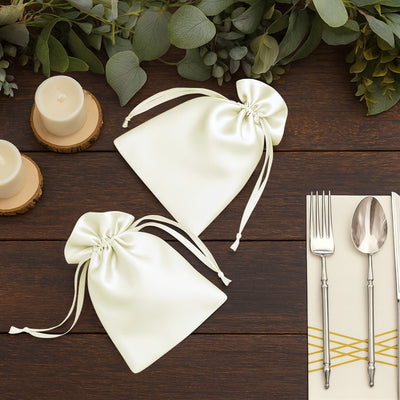 Elegant ivory satin favor bags on a rustic wooden table.