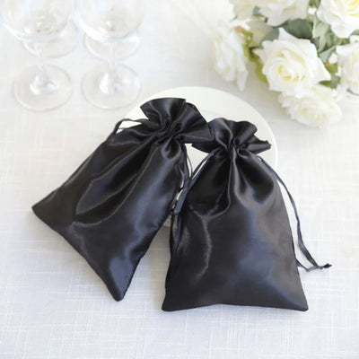 Two elegant black satin drawstring bags on a white table.
