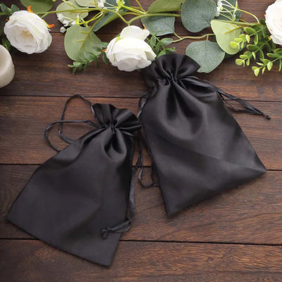 Two elegant black satin drawstring bags on a wooden surface.