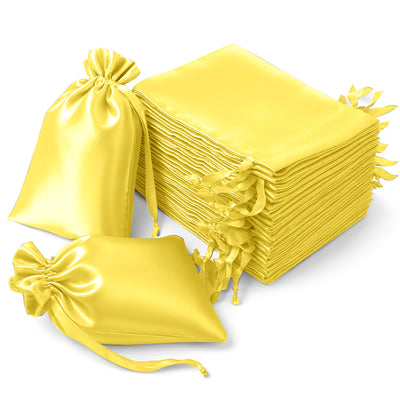 Yellow satin drawstring bags stacked and arranged on a plain background.