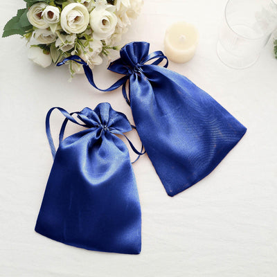 Blue satin drawstring gift bags arranged with flowers and a candle.