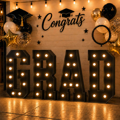 Graduation party backdrop with illuminated GRAAD letters and black gold balloons