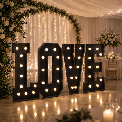 Illuminated LOVE sign at elegant wedding reception with floral decor