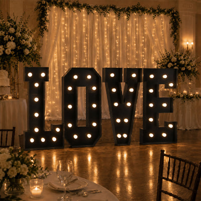 Illuminated LOVE sign at romantic wedding reception with floral decor
