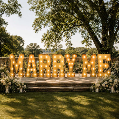 Outdoor wedding “Marry Me” proposal sign with lights and white roses