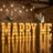 Large illuminated “MARRY ME” wedding proposal sign with floral arrangements indoors