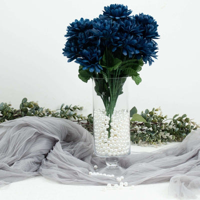 Navy blue flower bouquet in a clear vase with pearls and greenery accents.