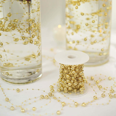 Gold decorative beads on a spool with glass vases in the background.