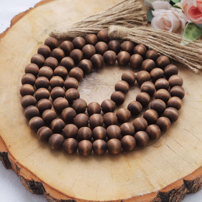 Brown wooden bead garland on a wooden surface with decorative flowers.