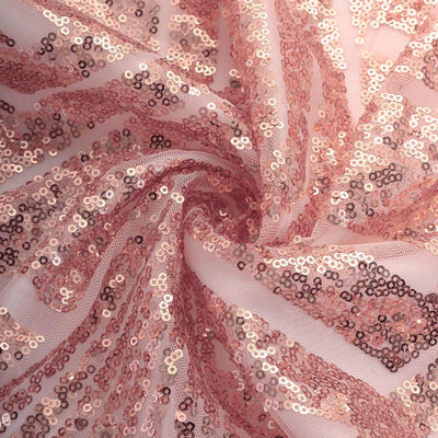 Rose gold sequin fabric with a shimmering texture in a swirling pattern.