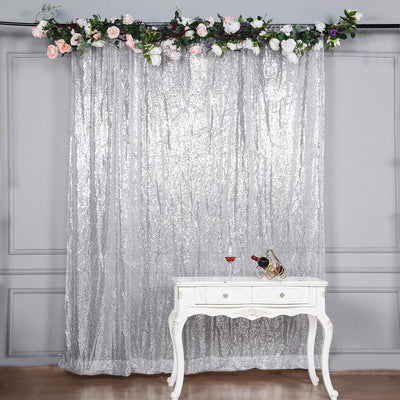 Silver sequin backdrop with floral decor and elegant table setting.
