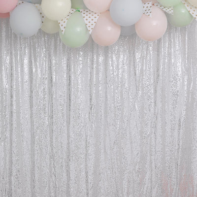 Colorful balloons with polka dot banners against a shimmering silver backdrop.