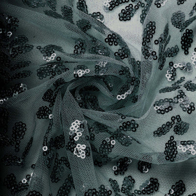 Green tulle fabric with black sequins in a swirling pattern.