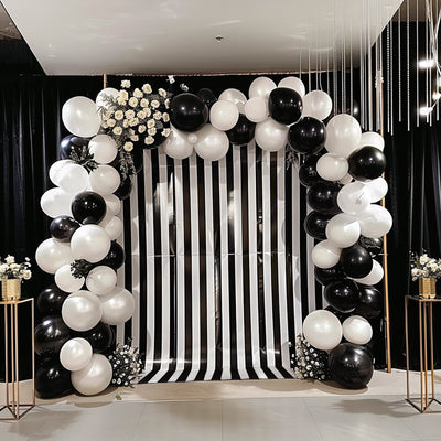 Black and white balloon arch with floral accents for event decoration.