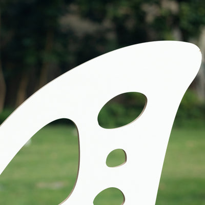 White modern chair design with unique cutout details against a blurred outdoor background.