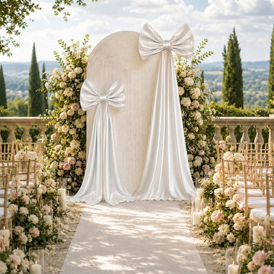 Elegant outdoor wedding ceremony backdrop with white bows and floral arch