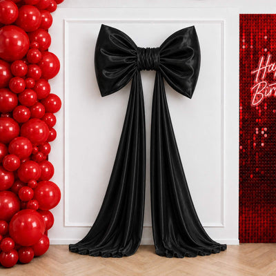 Black satin bow wall decor with red balloon birthday backdrop