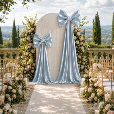 Elegant outdoor wedding ceremony aisle with blue bows and floral arch backdrop