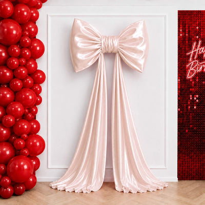 Elegant pink satin bow backdrop with red balloon and sequined birthday decor