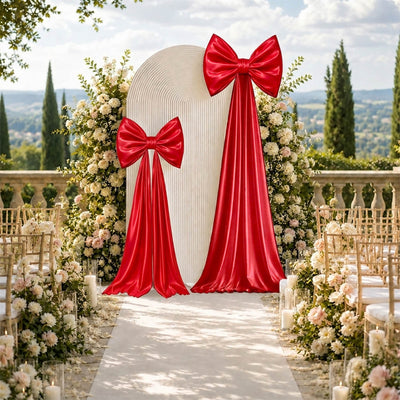 Luxury outdoor wedding aisle with red bows, floral arch, and scenic garden backdrop