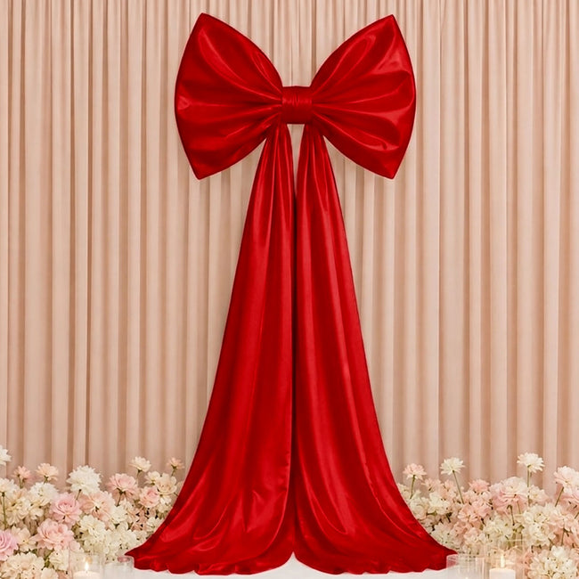 Red satin bow drape backdrop with cream curtain and floral floor decor