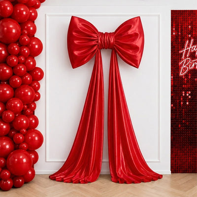 Red satin bow and draped ribbon wall decor with balloon backdrop