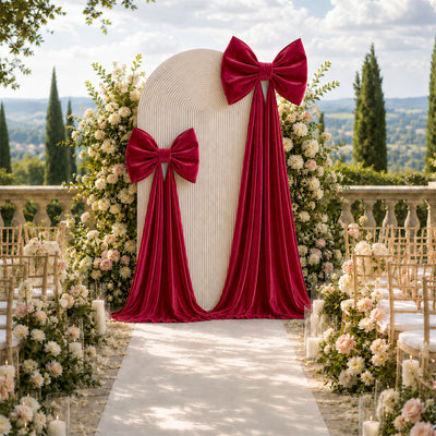 Elegant outdoor wedding aisle with burgundy bows, floral arch, and scenic hillside view