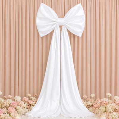 Elegant white bow wedding backdrop with floral arrangement and draped fabric