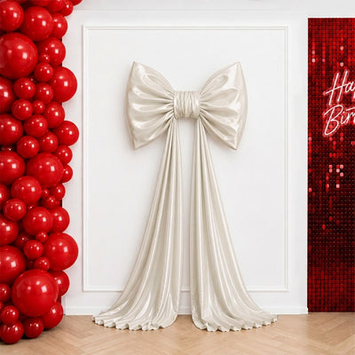 Elegant cream bow backdrop with red balloon wall and birthday sequin panel