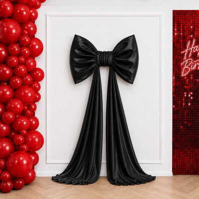 Black bow backdrop with red balloon arch and sequined birthday wall
