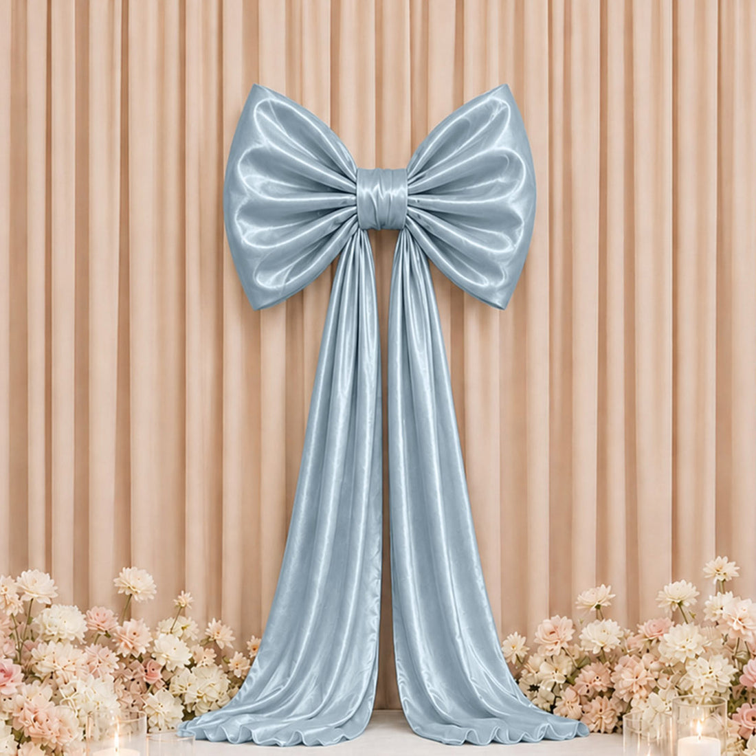 Elegant silver satin bow backdrop with floral decor and draped ribbon.
