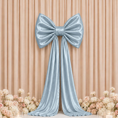 Elegant silver satin bow backdrop with floral decor and draped ribbon.