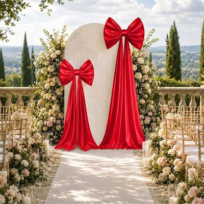 Outdoor wedding aisle with red bow backdrop and white floral decorations