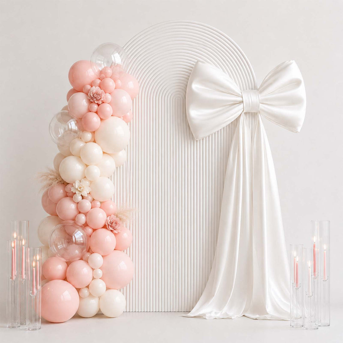 Pastel pink balloon arch and white bow backdrop for elegant party decor