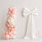 Pastel pink balloon arch and white bow backdrop for elegant party decor