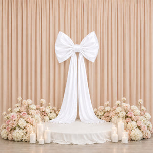 Elegant wedding backdrop with white bow, blush flowers, and candles