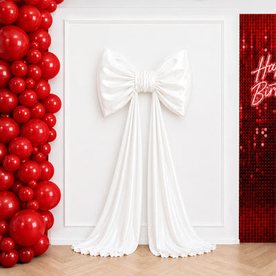 White satin bow backdrop with red balloons and sequin birthday wall
