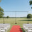Outdoor wedding setup with a red carpet and empty chairs in a scenic field.