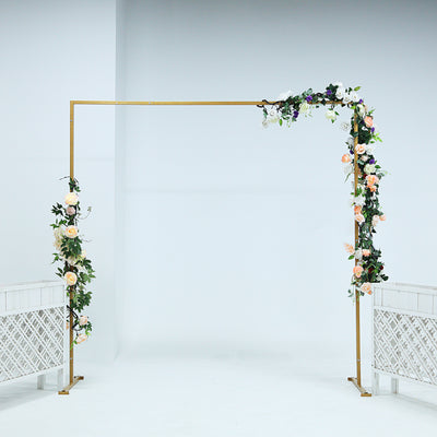 Floral wedding arch with gold frame and mixed flowers on a plain backdrop