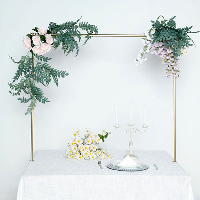 Elegant floral arch decor above a table setting with candles and a cake.