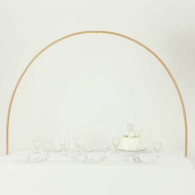 Elegant table setting with cake and glassware under a gold arch