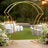 Elegant gold wedding arch with floral arrangements, set in a beautiful outdoor venue.